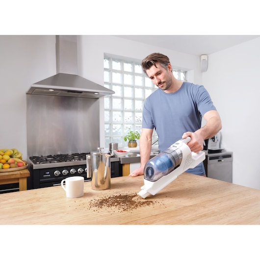 BLACKDECKER BHFEA420J cordless handheld vacuum cleaning coffee grounds on kitchen table.