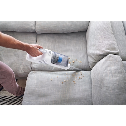 Photo of BLACKDECKER BHFEA420J stick vacuum cleaning crumbs from a light gray sofa.