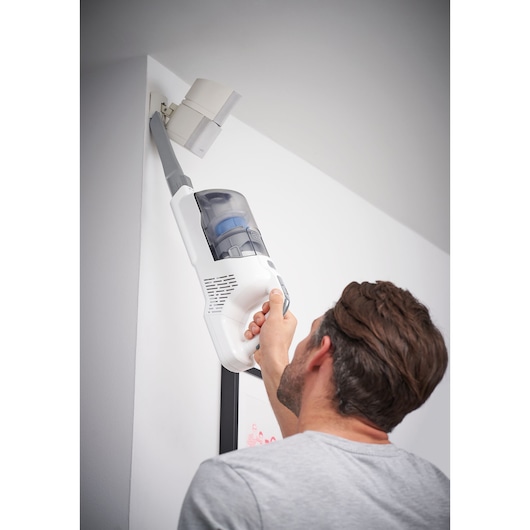 BLACKDECKER BHFEA420J handheld vacuum cleaning upper wall corner, photography indoor setting.