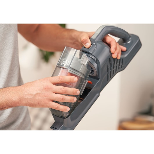 Photography of BLACKDECKER BHFEA520J vacuum cleaner with hand removing dust container.