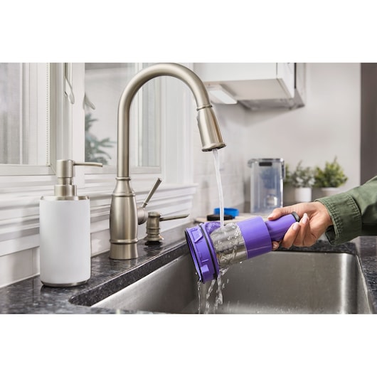 Photo of BLACKDECKER BHFEA640WP vacuum filter being rinsed under kitchen faucet in modern sink.