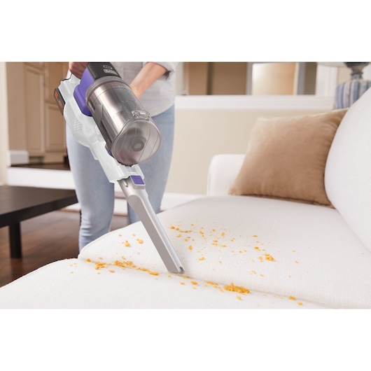 BLACKDECKER BHFEV1825CP cordless vacuum cleaning crumbs from white sofa in living room