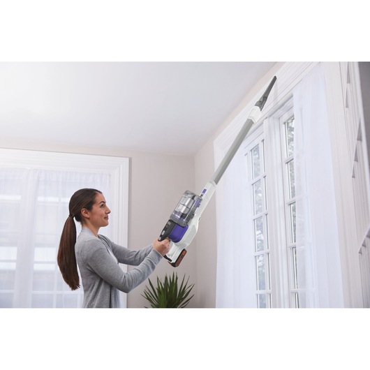 BLACKDECKER BHFEV1825CP cordless vacuum cleaner with extension cleaning high window trim indoors.