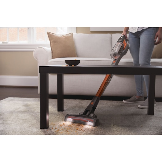 BLACKDECKER BHFEV182B cordless stick vacuum cleaning crumbs from carpet in living room setting.