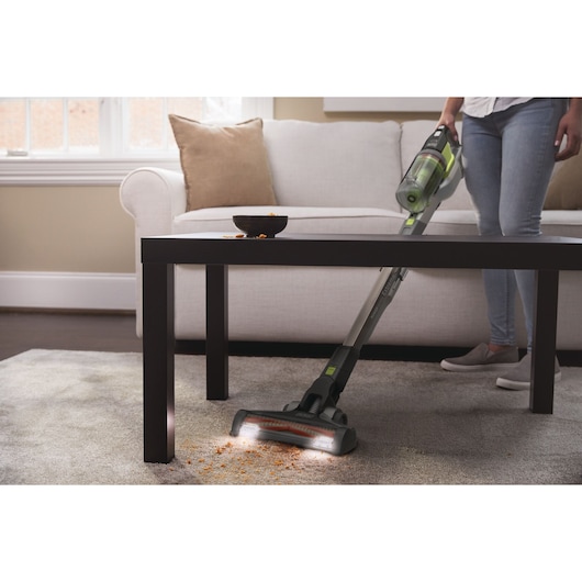 Photo of BLACKDECKER BHFEV362DA cordless vacuum cleaning crumbs from carpet in living room under coffee table.