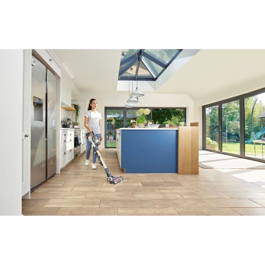 Photo of BLACKDECKER BHFEV36B2DW cordless stick vacuum cleaner in use on kitchen floor with blue island.