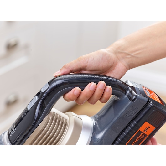 Photo of BLACKDECKER BHFEV36B2DW vacuum handle with hand holding ergonomic black grip, orange label visible.