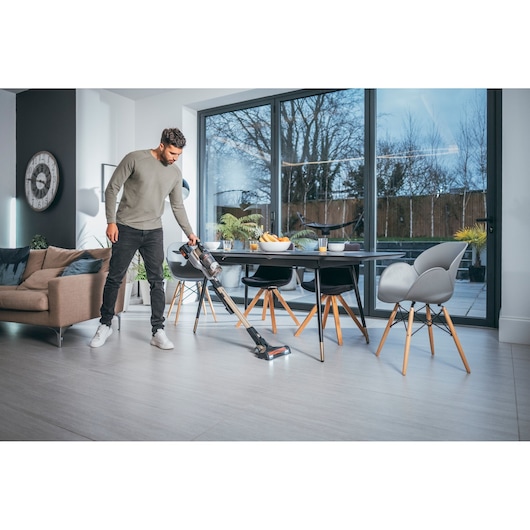 BLACK+DECKER BHFEV36B2DW cordless stick vacuum used on light floor in modern living and dining room.