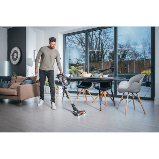 BLACKDECKER cordless stick vacuum BHFEV36B2DW in use on living room floor near dining area.
