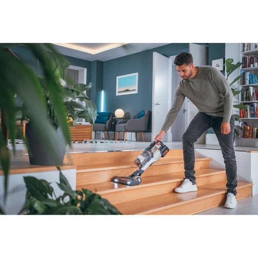 BLACKDECKER BHFEV36B2DW cordless vacuum used on wooden stairs in a modern living room.