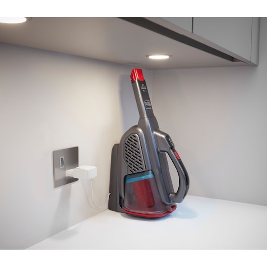 BLACKDECKER BHHV315B handheld vacuum cleaner charging on a white countertop, side angle.