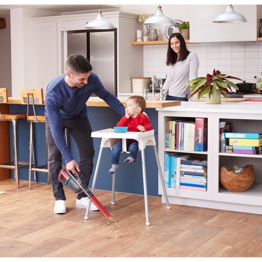 BLACKDECKER BHHV315J handheld vacuum cleaning crumbs near high chair in modern kitchen.