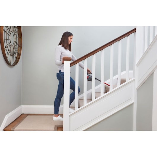 BLACKDECKER BHHV315J handheld vacuum cleaning carpeted stairs in home setting.