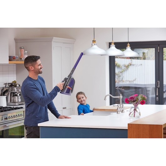 BLACKDECKER BHHV520BFP cordless handheld vacuum cleaning ceiling light in modern kitchen, flowers on counter.