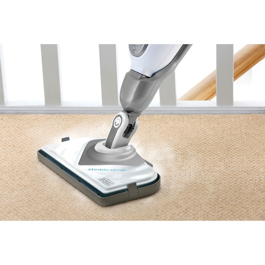 BLACKDECKER BHSM1615DSG steam mop cleaning beige carpet in a home setting.
