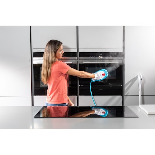 BLACKDECKER BHSM1615DSG steam cleaner being used on kitchen oven door, person holding cleaning head releasing steam.