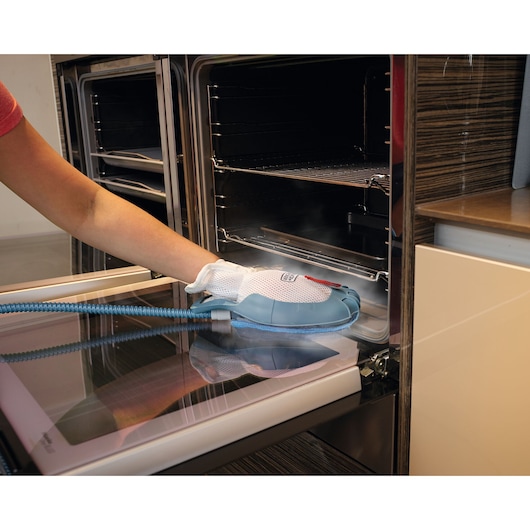 BLACKDECKER BHSM1615DSM steam cleaning glove cleaning an oven door, person’s hand shown using product.