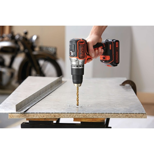 BLACKDECKER BL188KB cordless drill used to drill metal sheet, close-up of tool in action.