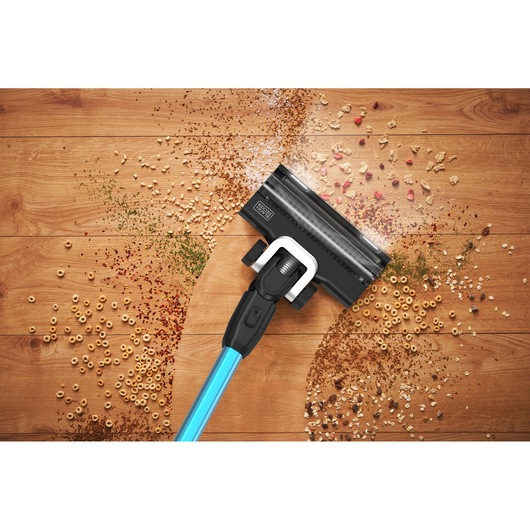 BLACKDECKER BSV520BRB cordless vacuum cleaning cereal and debris on wooden floor, top angle.