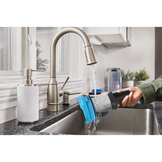 BLACK+DECKER BSV520BRB vacuum filter being rinsed under kitchen faucet, close-up view.