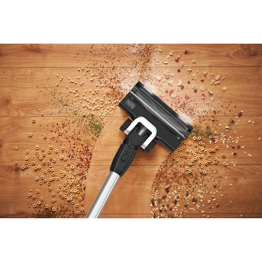 BLACKDECKER BSV520BRP cordless vacuum cleaning cereal and crumbs on wood floor, top view.