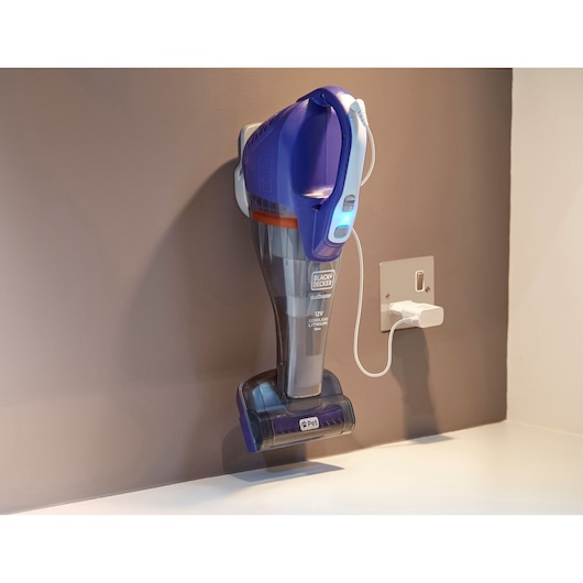 BLACKDECKER DVB315JP handheld vacuum in blue and grey charging on wall mount, pet brush visible.