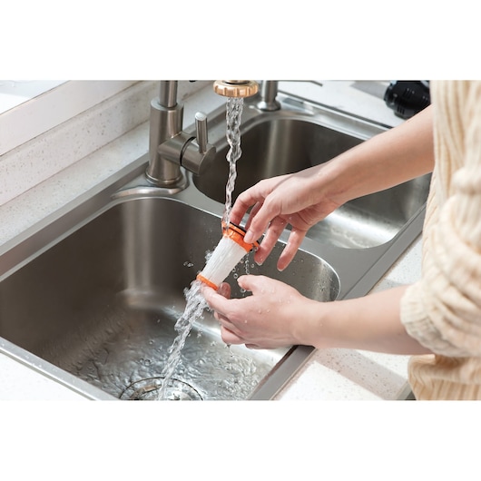 BLACKDECKER DVC320B21 vacuum filter being rinsed under faucet in kitchen sink.