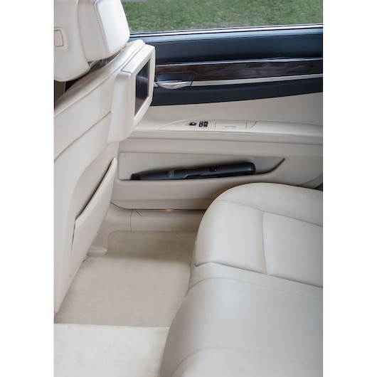 BLACKDECKER DVC320B21 handheld vacuum stored in beige car door pocket, photo taken from passenger side.