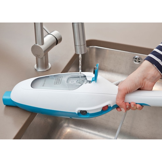 Photo of BLACK+DECKER FSM13E1 steam cleaner water tank being filled from a kitchen faucet.