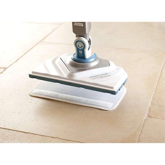 BLACKDECKER FSM1616 steam mop close-up on tile floor, white and blue base with cleaning pad, side angle.