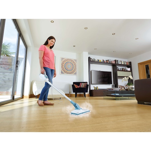 BLACKDECKER FSMH1300FX steam mop cleaning a wooden floor in a modern living room, photography from side angle.