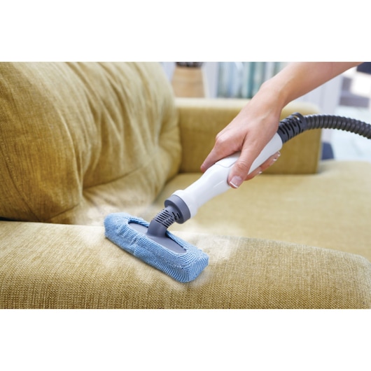 BLACKDECKER FSMH1321 steam cleaner with blue microfiber pad cleaning a yellow sofa upholstery.