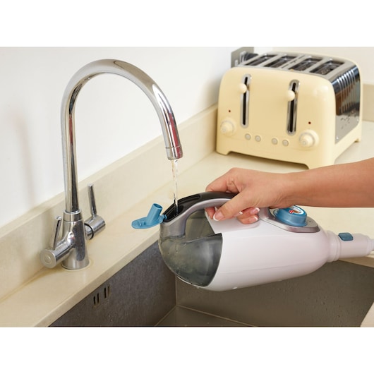 Photo of BLACKDECKER FSMH1321 steam cleaner water tank being filled at a kitchen sink.