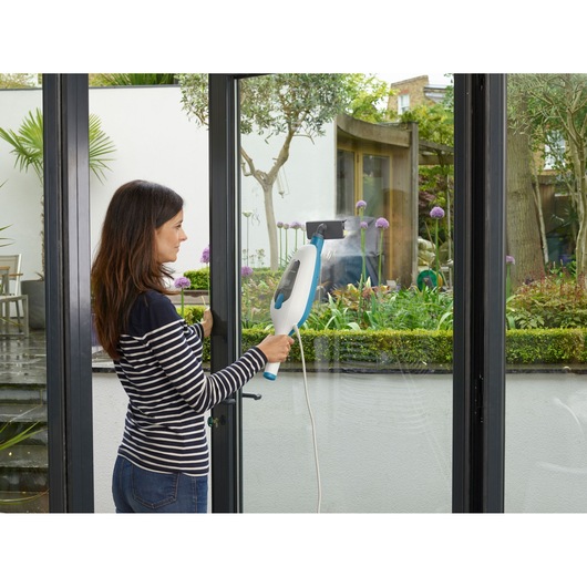 Photo of BLACKDECKER FSMH13E10 steam cleaner used on glass doors in a modern home interior.