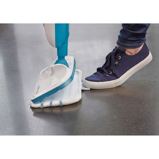 BLACKDECKER FSMH13E5 steam mop with microfiber pad on floor, person in navy sneaker pressing pad.