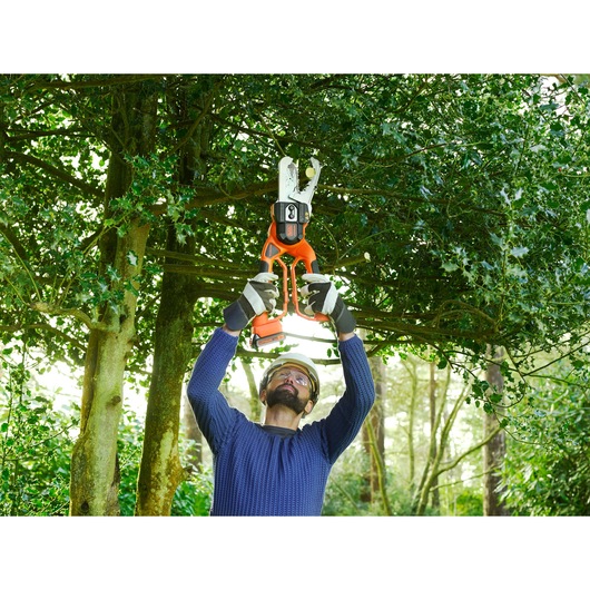 BLACKDECKER GKC1000L cordless pruner used outdoors for cutting tree branches.