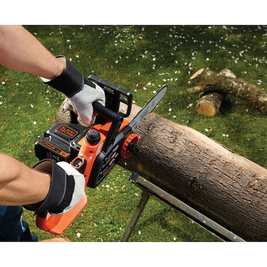 BLACKDECKER GKC1825LB lithium battery chainsaw in use cutting a log outdoors, close-up view.