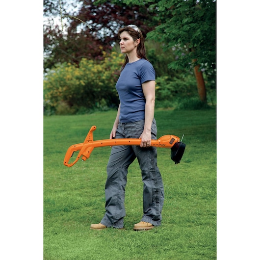 BLACKDECKER GL310 orange grass trimmer held by person outdoors on green lawn.