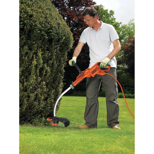 BLACKDECKER GL9035 orange electric grass trimmer used outdoors on lawn near hedge.