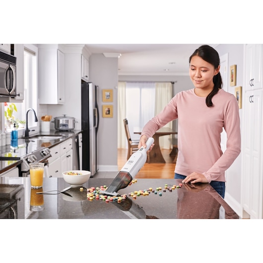 BLACKDECKER HLVC315J11 handheld vacuum cleaning spilled cereal on kitchen counter.