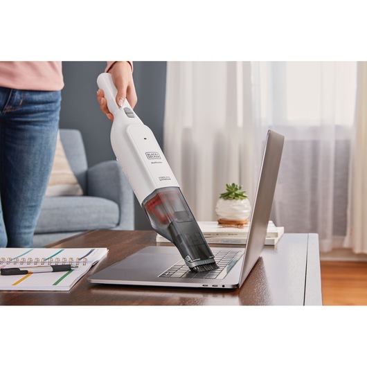 BLACKDECKER HLVC315J11 handheld vacuum cleaning laptop keyboard in home setting.