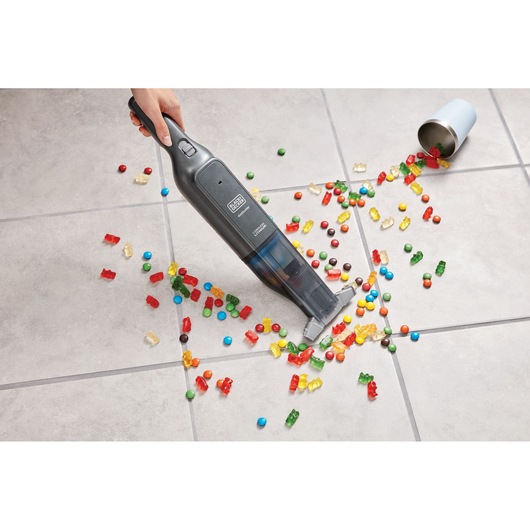 BLACKDECKER HLVC320B11 cordless hand vacuum cleaning spilled candy on tile floor, top view.
