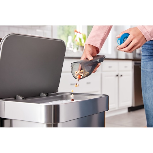 BLACKDECKER HLVC320B11 handheld vacuum dust bin emptied into kitchen trash can.
