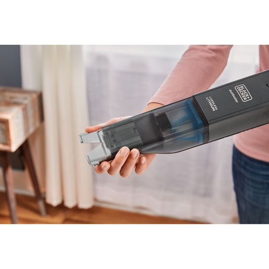 Photo of BLACKDECKER HLVC320B11 cordless handheld vacuum with transparent dustbin, held in a person's hand indoors.