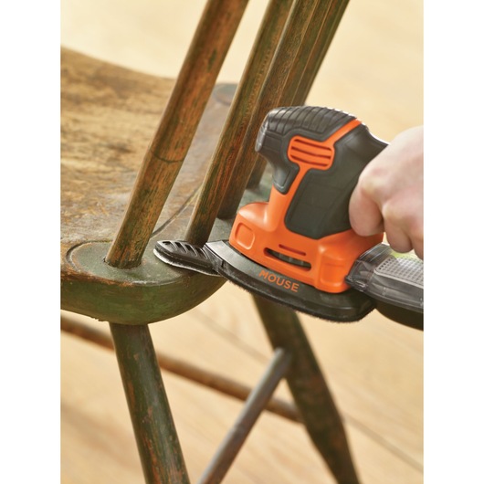 BLACKDECKER KA2000 mouse sander sanding a wooden chair, close-up angle.