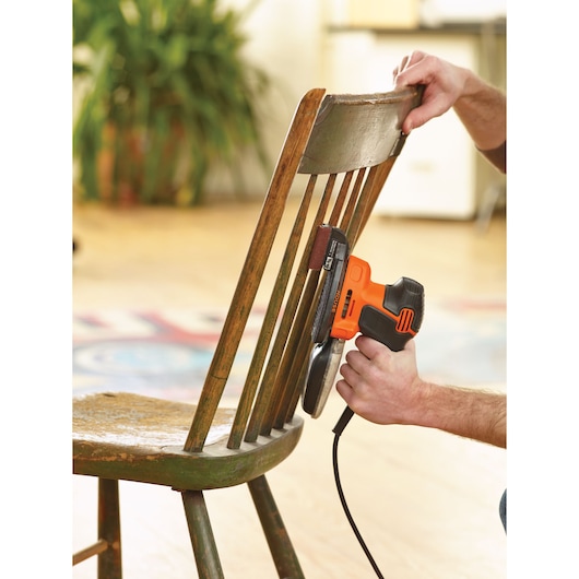 BLACKDECKER KA2000 electric sander sanding wooden chair spindles in indoor setting.