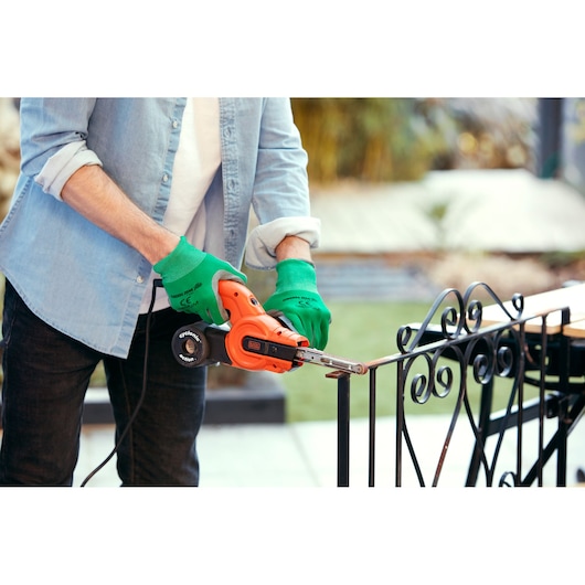 BLACKDECKER KA900E belt sander in use sanding metal railing, close-up view outdoors.