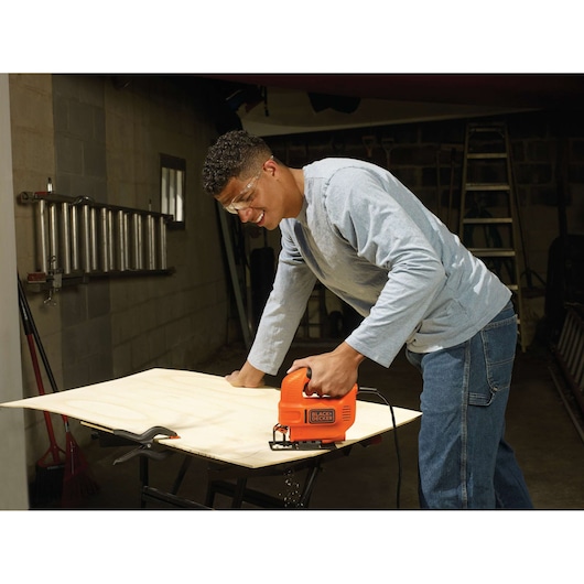 Photo of BLACKDECKER KS501 jigsaw cutting wood plank in workshop setting.