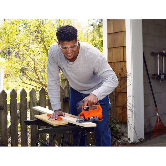 BLACKDECKER KS801SE jigsaw used for cutting wood outdoors on a workbench.
