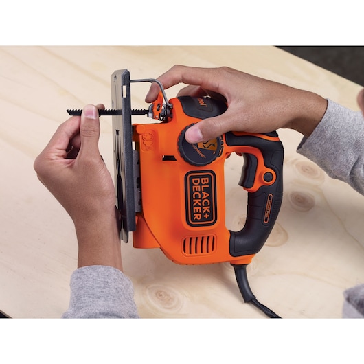 Photo of a BLACK+DECKER KS801SE jigsaw being equipped with a blade, orange and black handle visible.
